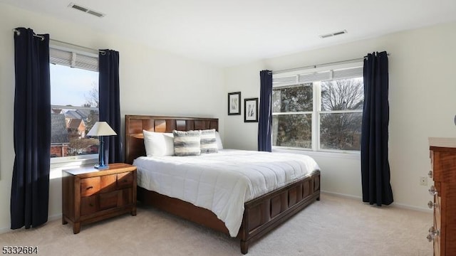 bedroom featuring multiple windows, visible vents, and light colored carpet