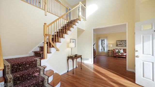 stairs with a high ceiling, baseboards, and wood finished floors