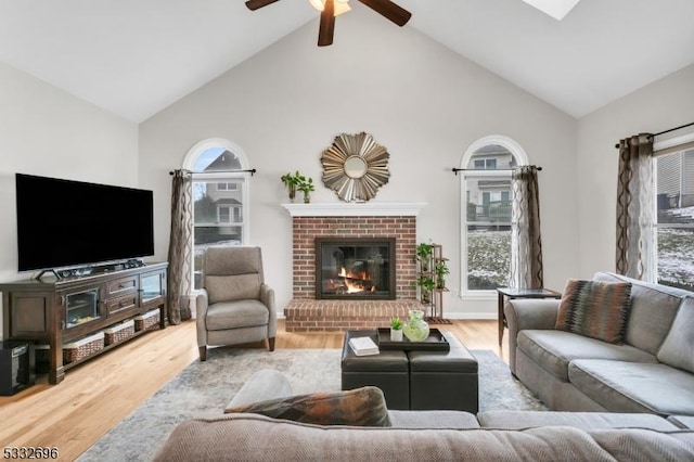 living room featuring vaulted ceiling, ceiling fan, hardwood / wood-style floors, and a fireplace