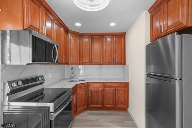 kitchen featuring appliances with stainless steel finishes, light wood-type flooring, light stone countertops, sink, and backsplash