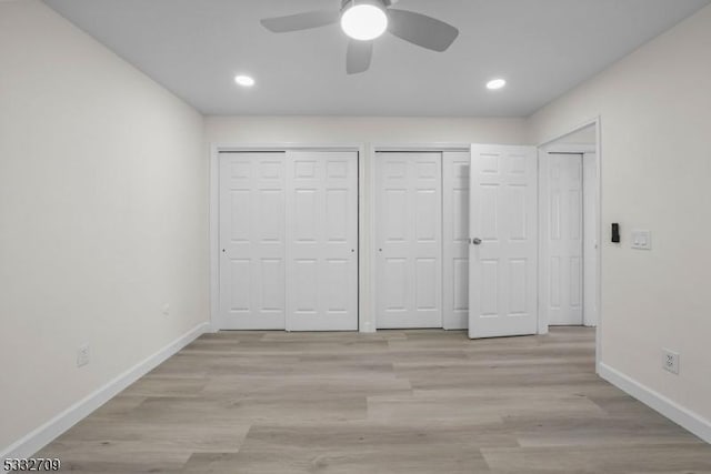 unfurnished bedroom featuring ceiling fan, light hardwood / wood-style floors, and two closets