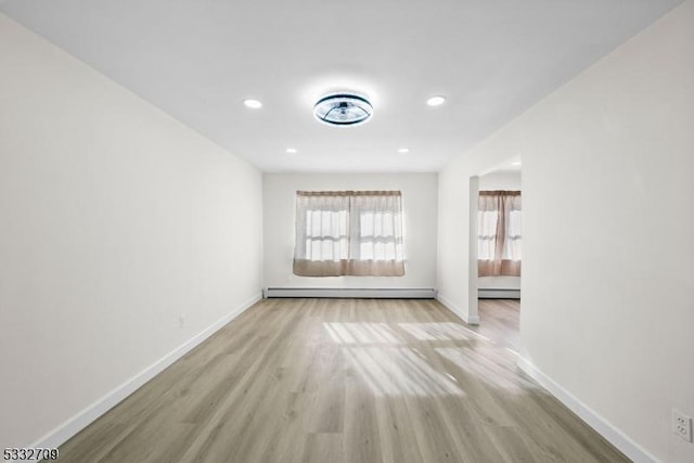 spare room with baseboard heating and light wood-type flooring