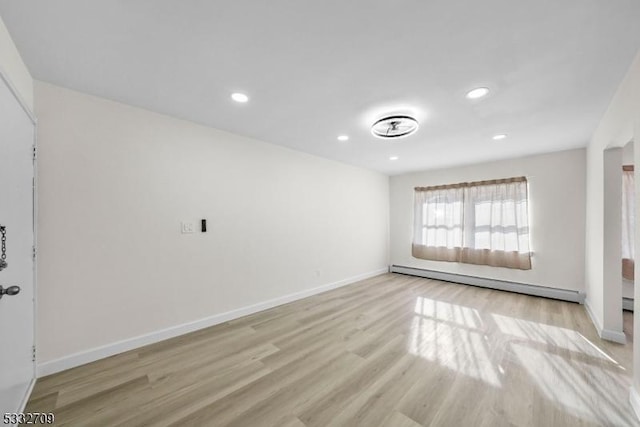 unfurnished room featuring baseboard heating and light hardwood / wood-style floors