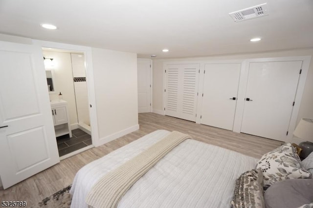 bedroom featuring connected bathroom and light hardwood / wood-style flooring