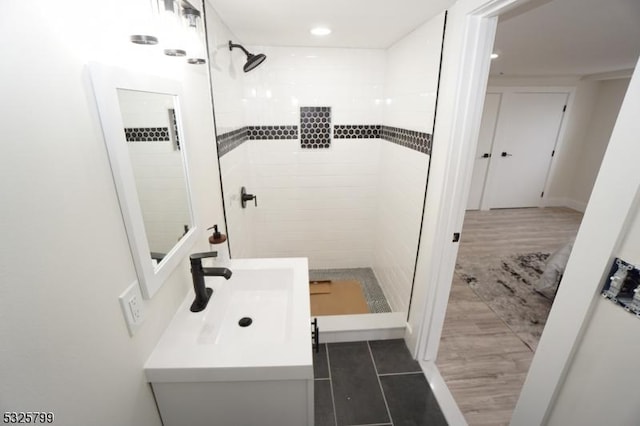 bathroom featuring a tile shower, vanity, and tile patterned floors