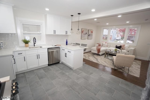 kitchen with kitchen peninsula, stainless steel dishwasher, sink, white cabinets, and hanging light fixtures