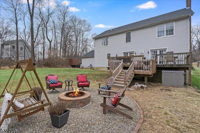 back of property with a yard, a fire pit, and a wooden deck