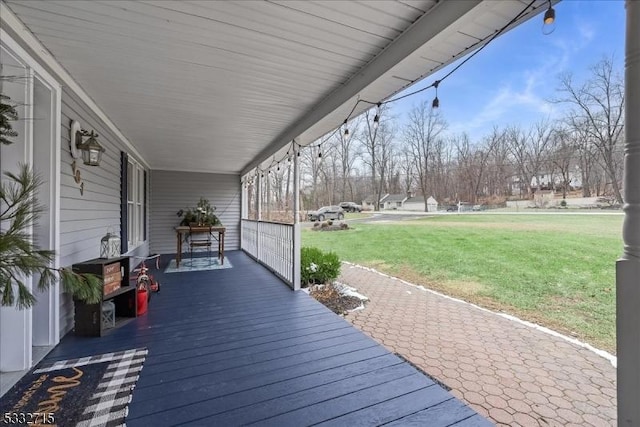 wooden terrace featuring a lawn and covered porch