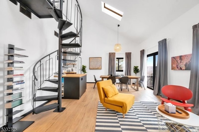 interior space with a towering ceiling, light hardwood / wood-style floors, and a skylight