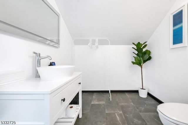 bathroom with toilet, vanity, and vaulted ceiling