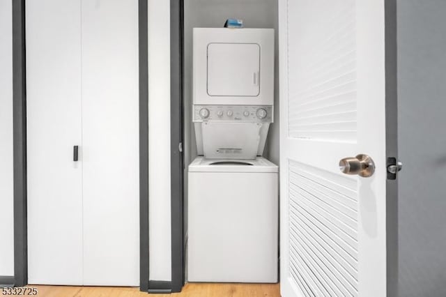 clothes washing area with stacked washer and clothes dryer and light hardwood / wood-style floors