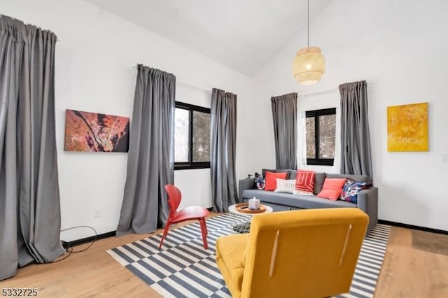 sitting room with high vaulted ceiling, a wealth of natural light, and wood-type flooring