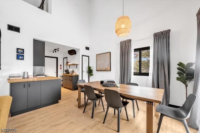 dining area featuring a high ceiling and light wood-type flooring