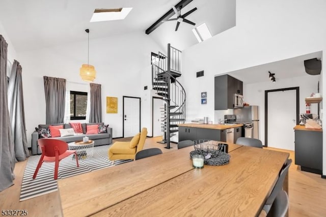 dining space with a skylight, beamed ceiling, ceiling fan, high vaulted ceiling, and light hardwood / wood-style flooring