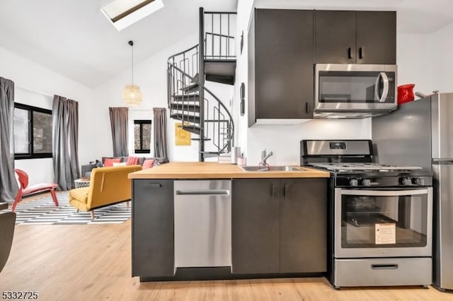 kitchen featuring appliances with stainless steel finishes, wood counters, pendant lighting, sink, and lofted ceiling