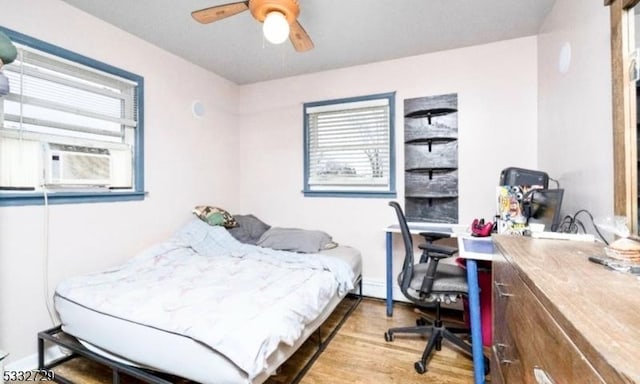 bedroom with ceiling fan, cooling unit, and wood-type flooring