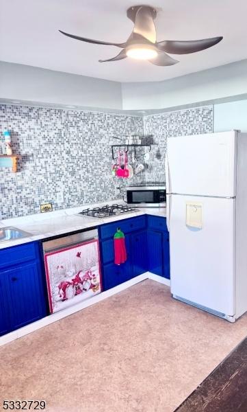 kitchen with white appliances, blue cabinets, tasteful backsplash, and sink