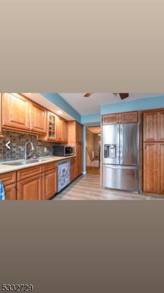 kitchen featuring appliances with stainless steel finishes, light hardwood / wood-style floors, tasteful backsplash, and sink