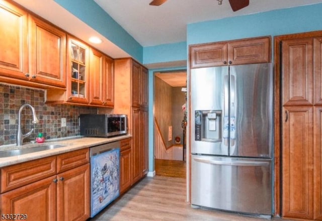 kitchen with stainless steel appliances, decorative backsplash, light wood-type flooring, ceiling fan, and sink