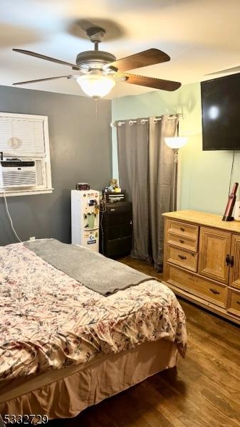 bedroom featuring ceiling fan, cooling unit, and dark hardwood / wood-style floors