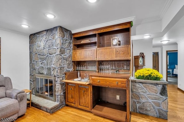 bar featuring a fireplace, light hardwood / wood-style floors, and ornamental molding