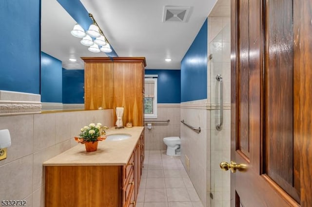 bathroom with walk in shower, tile patterned flooring, toilet, vanity, and tile walls