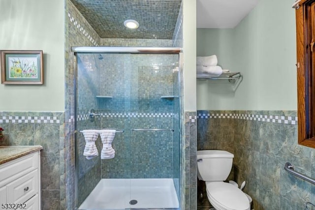 bathroom with a shower with door, vanity, and tile walls