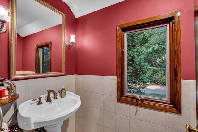 bathroom with tile walls, sink, and lofted ceiling