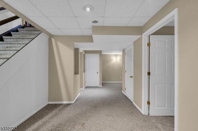 hall with carpet and a drop ceiling