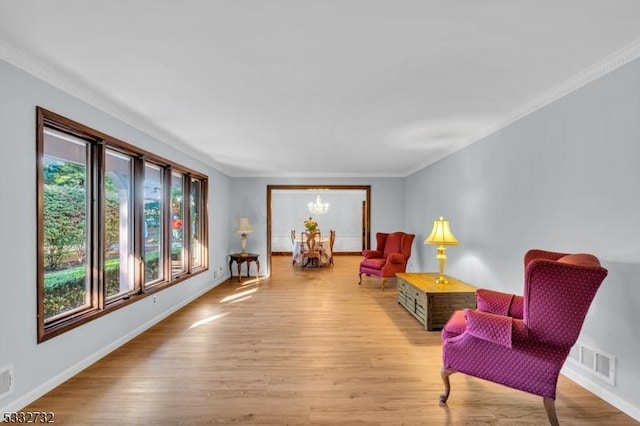 living area featuring light hardwood / wood-style flooring, ornamental molding, and a notable chandelier