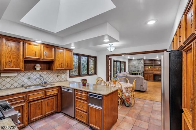 kitchen with kitchen peninsula, appliances with stainless steel finishes, backsplash, sink, and light tile patterned flooring