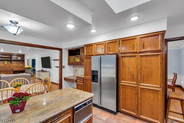 kitchen featuring light stone countertops, stainless steel fridge with ice dispenser, and decorative backsplash