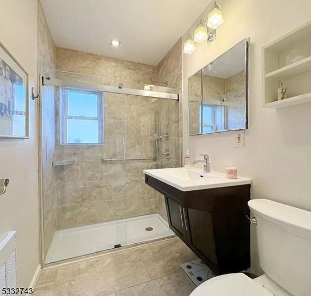 bathroom featuring toilet, vanity, and a shower with door