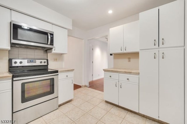 kitchen featuring white cabinets, appliances with stainless steel finishes, and tasteful backsplash