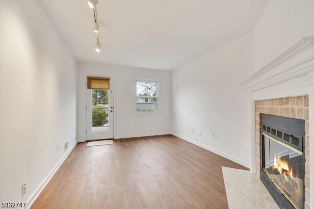 unfurnished living room featuring a high end fireplace, track lighting, and wood-type flooring