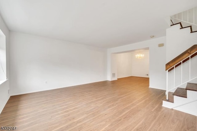 unfurnished living room with light hardwood / wood-style flooring and a notable chandelier