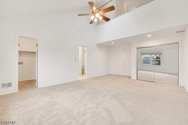 unfurnished living room featuring light carpet, ceiling fan, and high vaulted ceiling