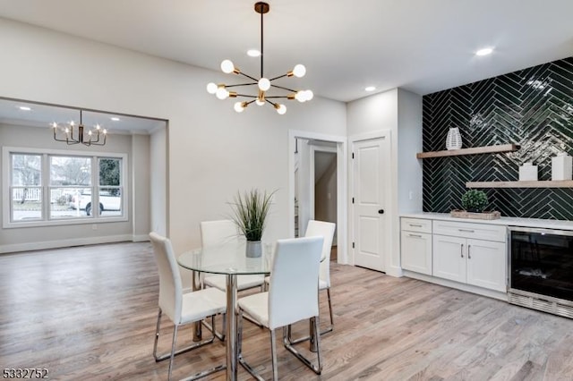 dining room featuring beverage cooler, an inviting chandelier, and light hardwood / wood-style floors