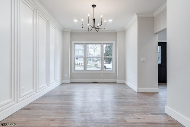 unfurnished dining area featuring ornamental molding, light hardwood / wood-style flooring, and a chandelier