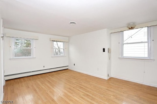 unfurnished room with light wood-type flooring and a baseboard heating unit