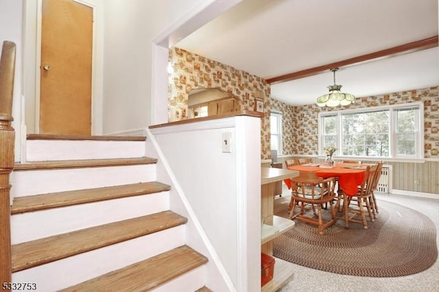 stairs with carpet floors and beamed ceiling