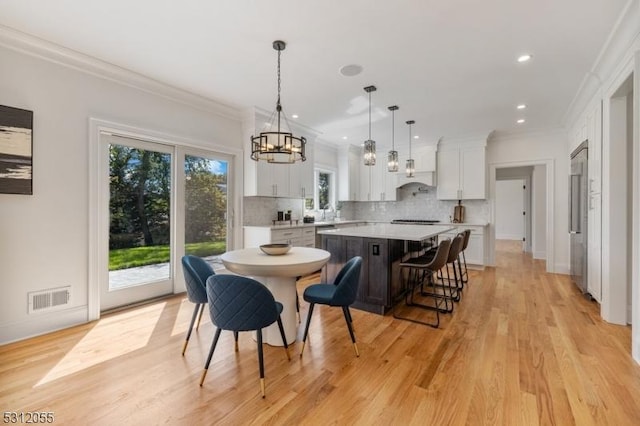 dining room with plenty of natural light, light wood-type flooring, and ornamental molding