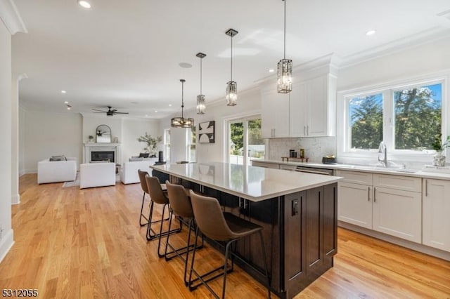 kitchen with ceiling fan, a center island, a kitchen breakfast bar, pendant lighting, and white cabinets