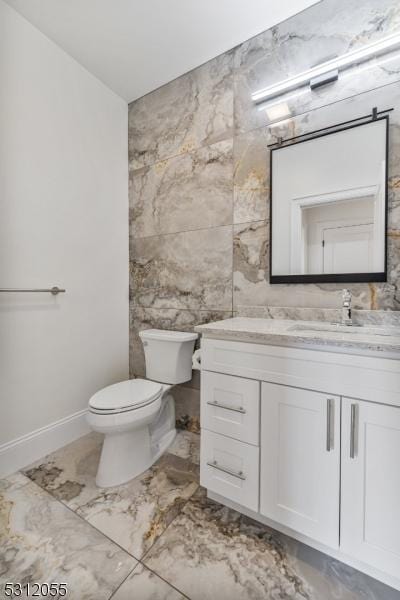 bathroom with vanity, tile walls, and toilet