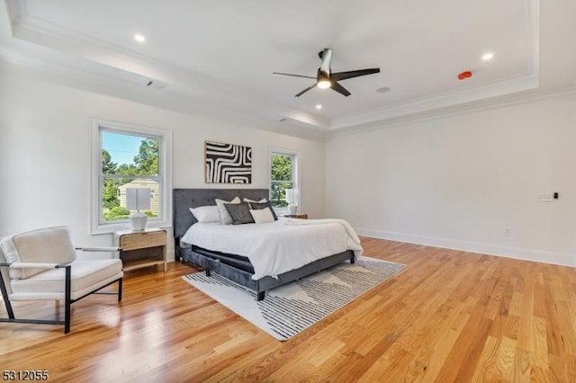 bedroom featuring hardwood / wood-style floors, ceiling fan, a raised ceiling, and ornamental molding