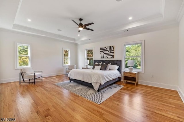 bedroom featuring a tray ceiling, ceiling fan, crown molding, and light wood-type flooring