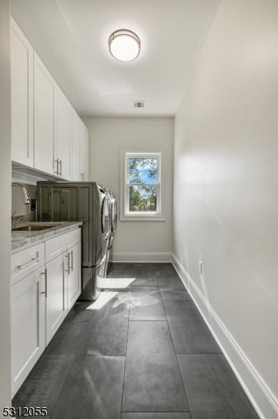 washroom with cabinets, sink, and washing machine and dryer