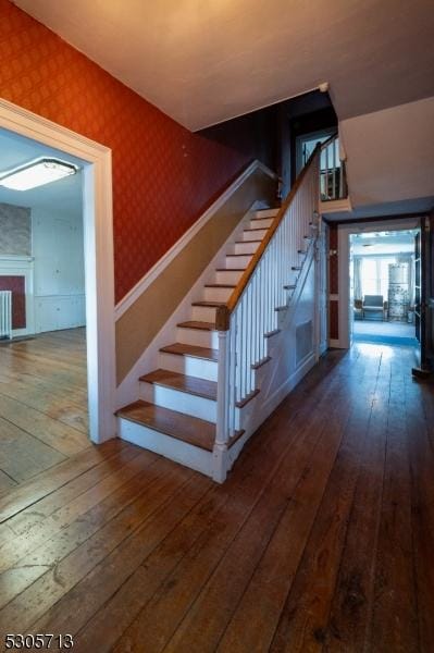 staircase featuring hardwood / wood-style floors, radiator heating unit, and a fireplace