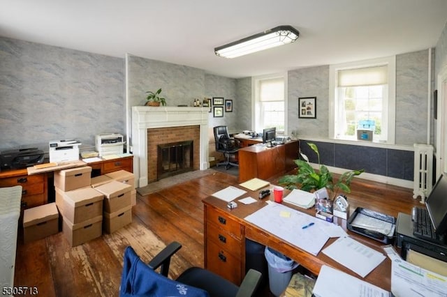 home office with dark wood-type flooring and a fireplace