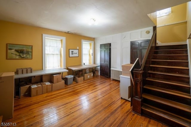 interior space featuring radiator, light wood-type flooring, and white cabinetry